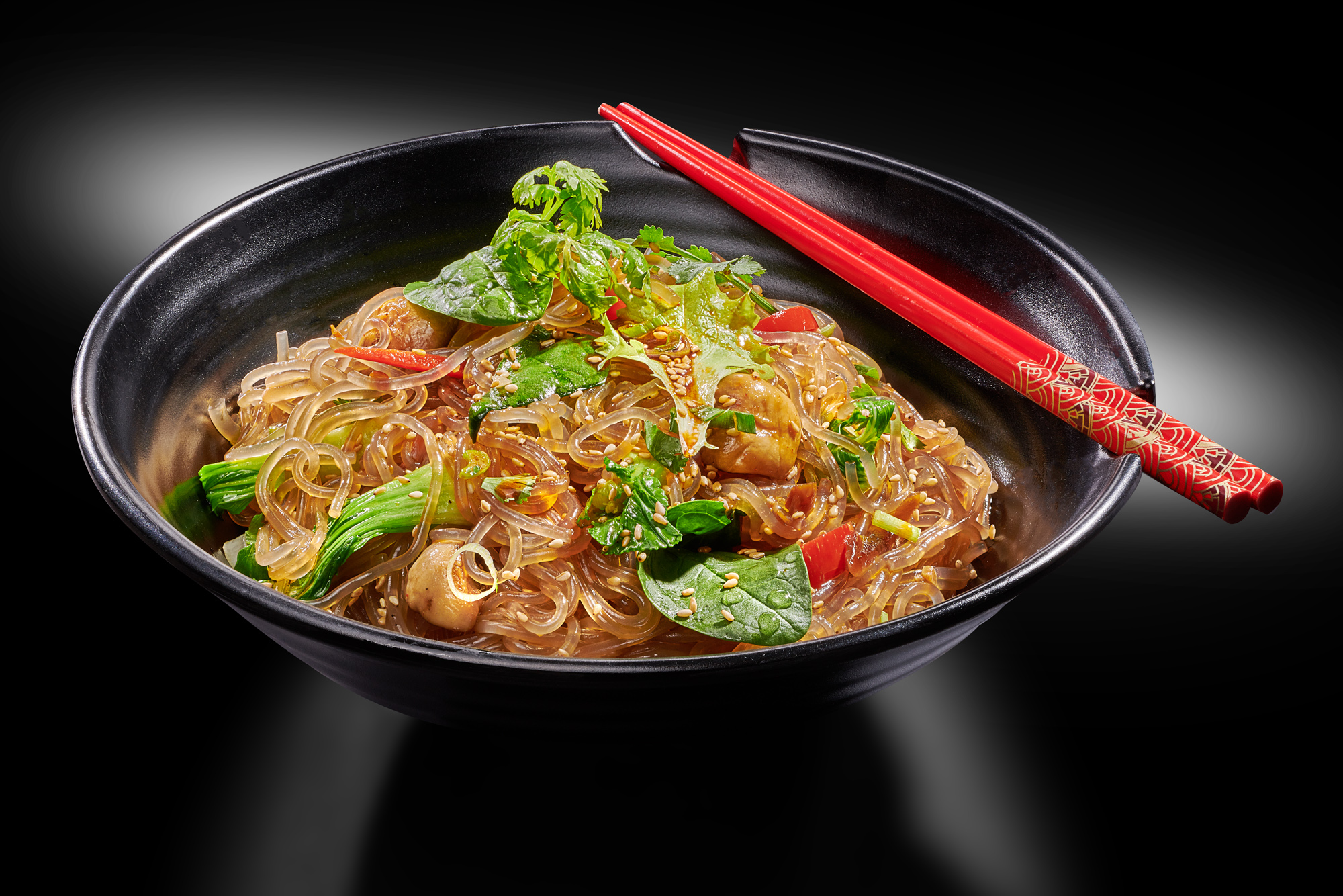 Foodfoto fokuspunkt GmbH Asiagourmet koreanisches Japchae auf dunklem Teller und schwarzem Hintergrund für Speisekarten