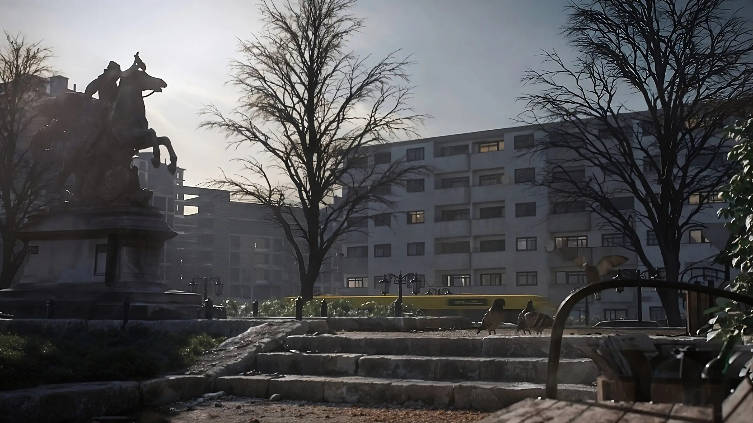 Stimmungsvolle Parkszene in einer urbanen Umgebung: Eine steinerne Treppe mit Tauben im Vordergrund führt zu einer imposanten Reiterstatue. Kahle Bäume und historische Straßenlaternen säumen den Weg. Im Hintergrund steht ein abgewohntes Wohngebäude, während ein gelber Bus vorbeifährt. Ein Bücherkorb deutet auf einen Straßenhändler hin. Die melancholische Atmosphäre wird durch weiches Licht und lange Schatten unterstrichen.